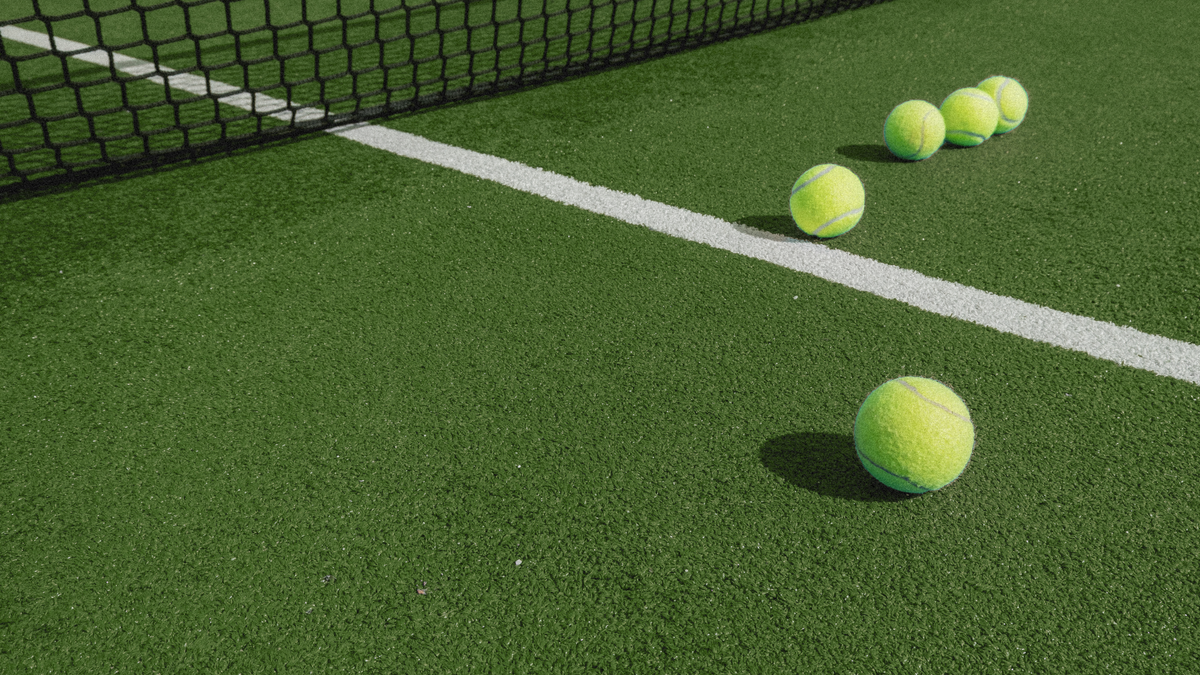 Tennis balls on a green court with a net in the background